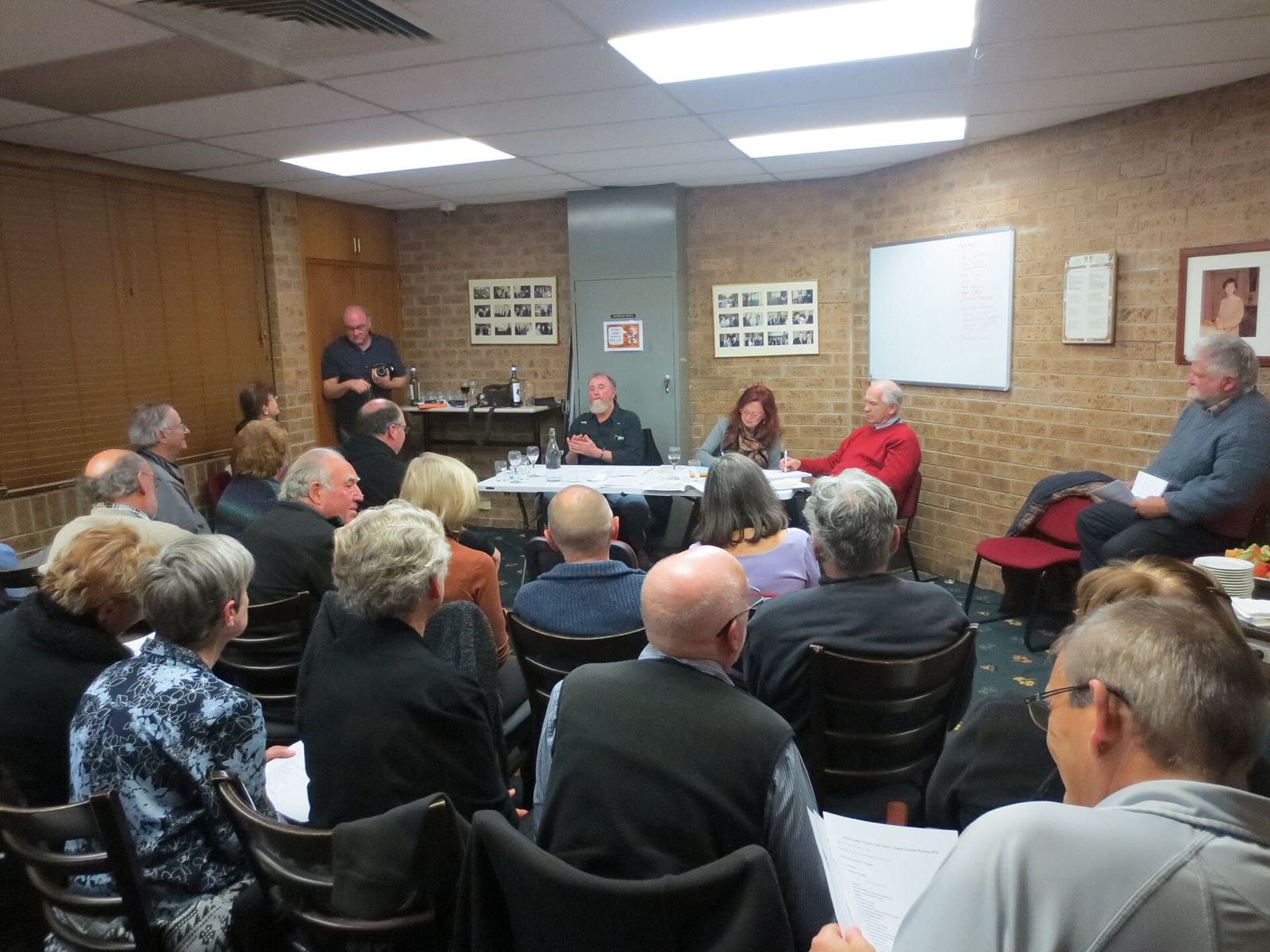 AGM of a typical very small volunteer non-profit organisation the Monaro Folk Society showing office holders sitting at table in background president secretary and public officer. 