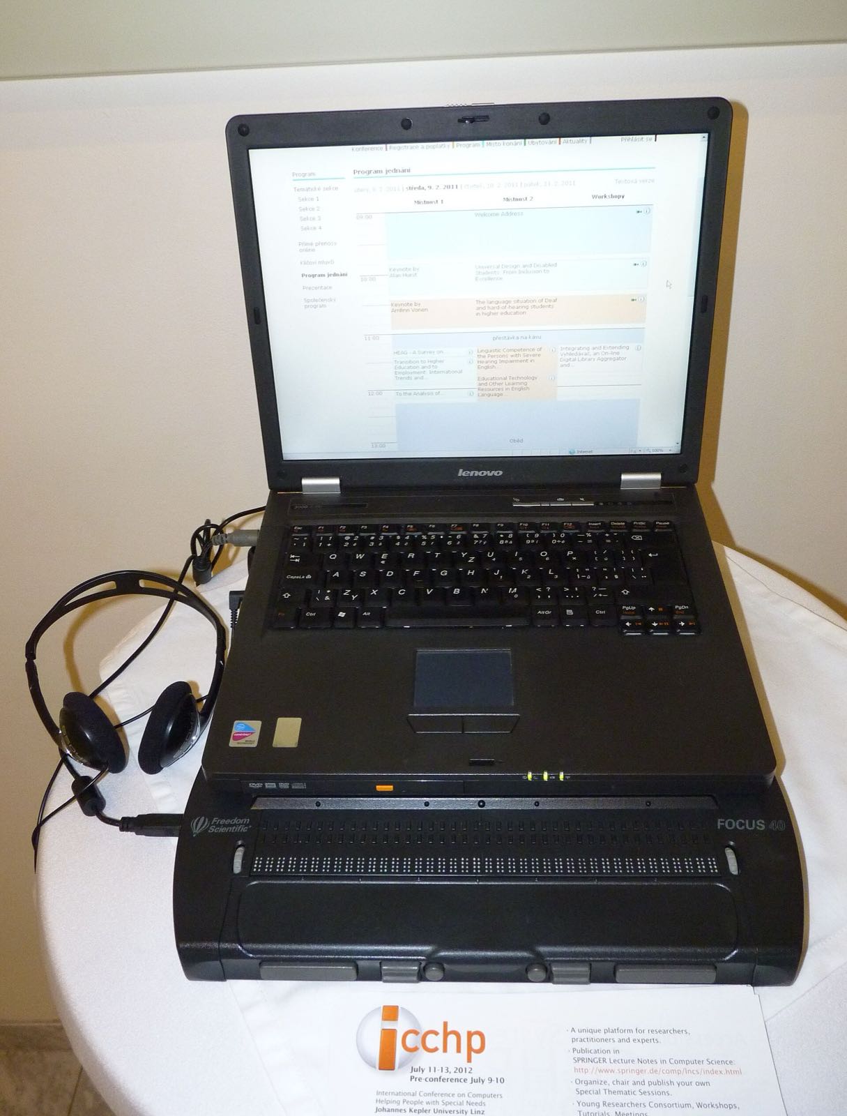 A laptop paired with a refreshable braille display at an accessibility conference.